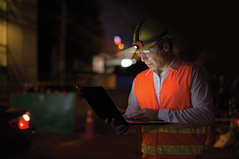 a man wearing an Energizer Intrinsically Safe Industrial Headlamp using a laptop in the dark