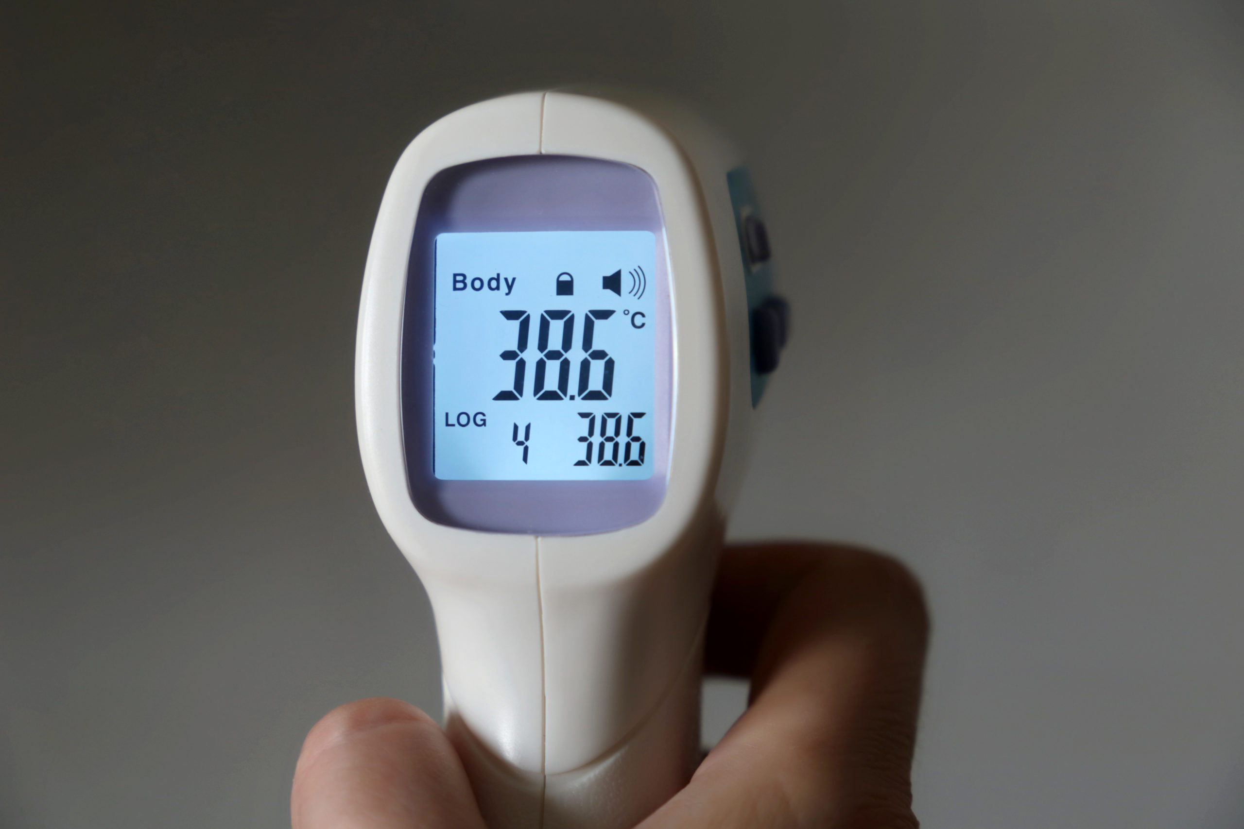 a person holding a digital thermometer displaying the body temperature