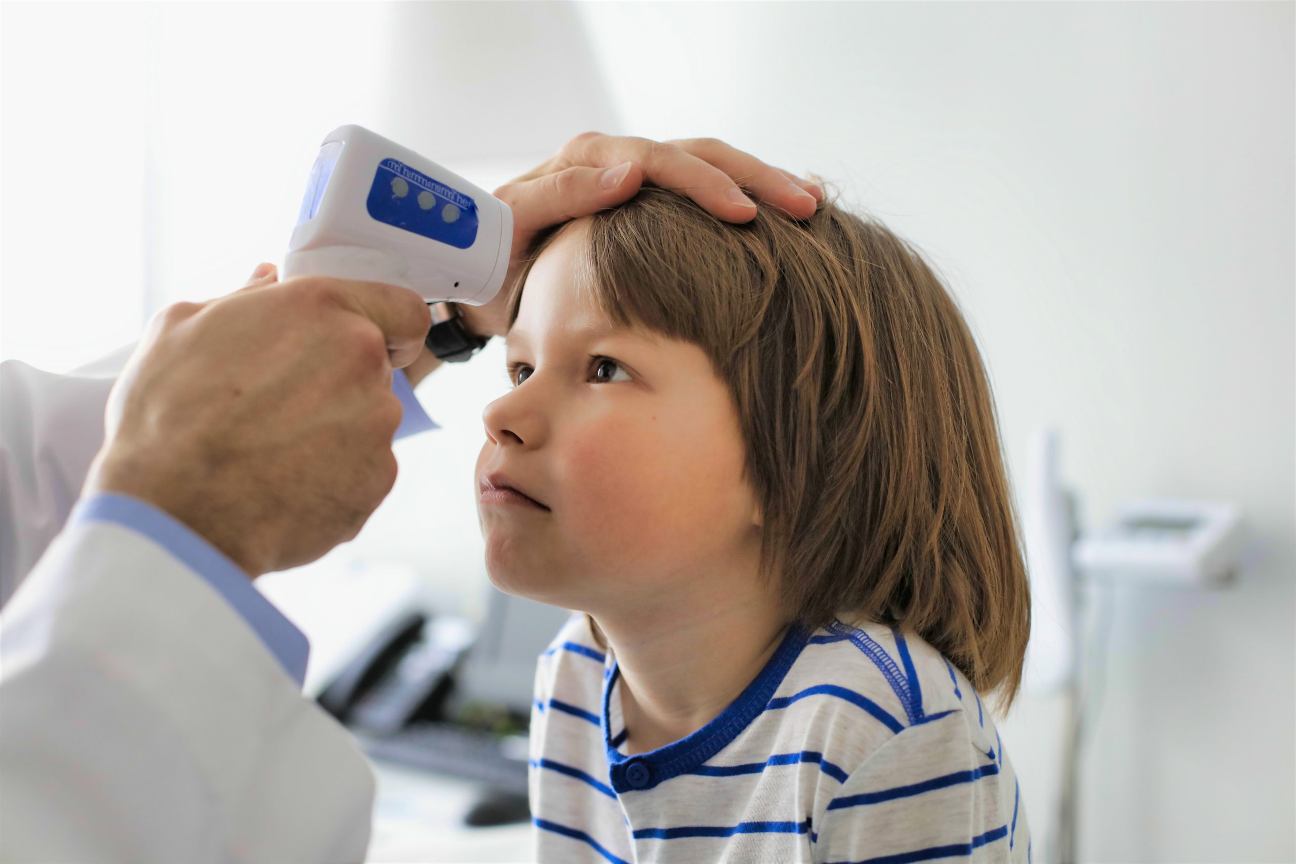 doctor measuring temperature of boy with infrared thermometer